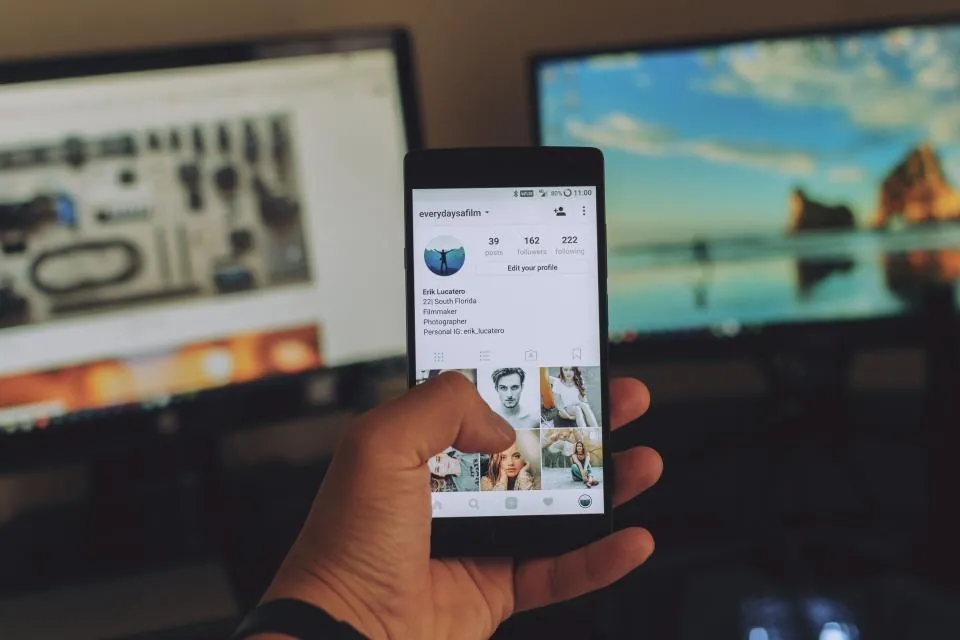 Monitörlerin önünde elde tutulan akıllı telefon, mobil Google aramasında yapay zekâ özetlerini temsil ediyor