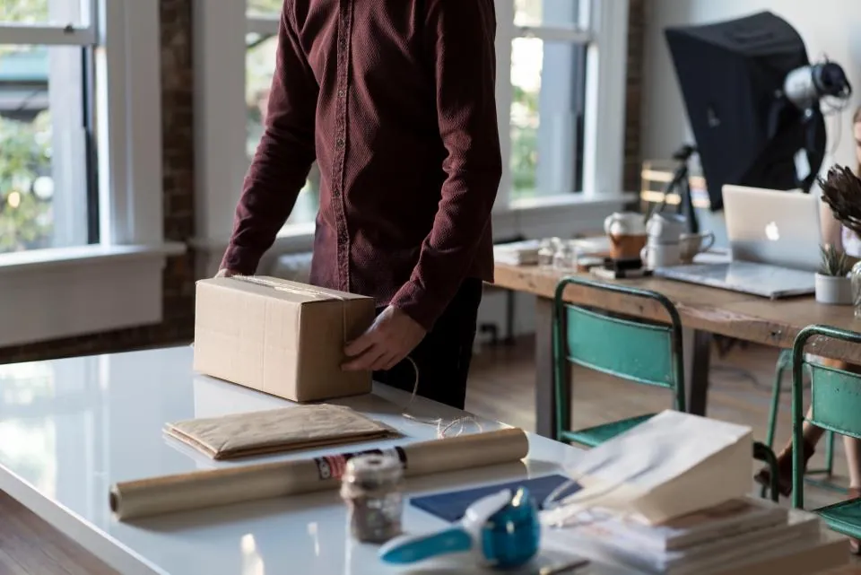 Ofiste e-ticaret siparişleri için karton kutuları paketleyen çalışan