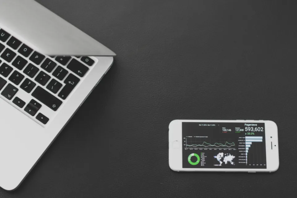 Masada dizüstü bilgisayar yanında dönüşüm verilerini gösteren analiz ekranlı akıllı telefon