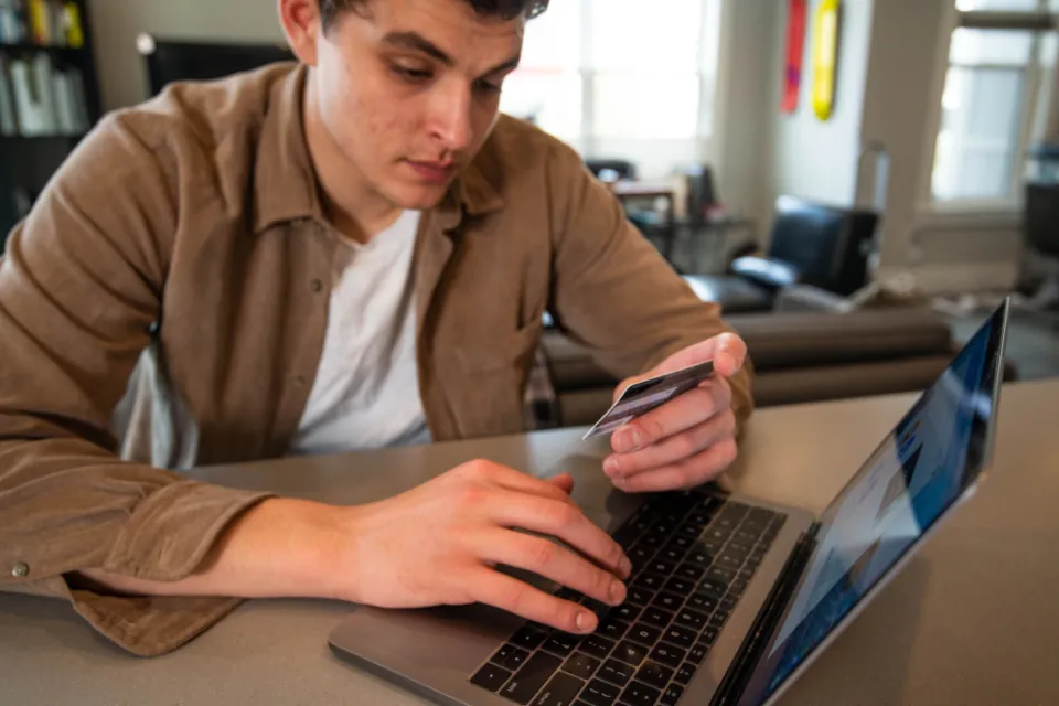 Dizüstü bilgisayarda kredi kartıyla online alışveriş yapan genç adam, e-ticaret altyapısı seçimi